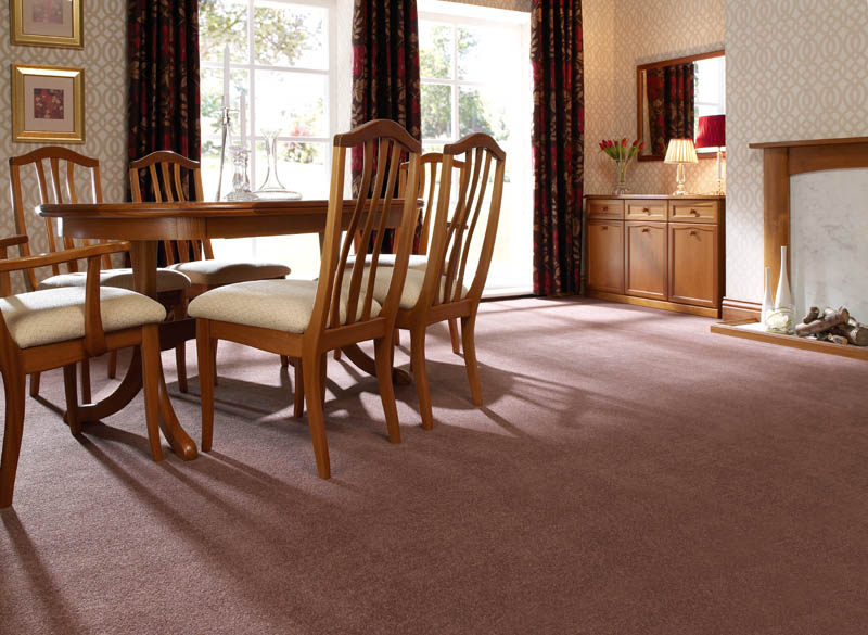 Mauve-brown carpet in a dining room with an oak table and chairs, beside a marble fireplace.